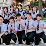 Cheerful group of students in uniform posing with thumbs up outdoors.