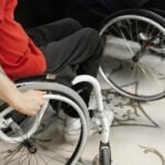 Close-up of person in wheelchair wearing red shirt, indoors.