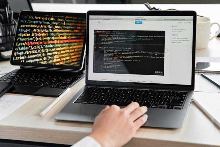 A developer writing code on a laptop, displaying programming scripts in an office environment.